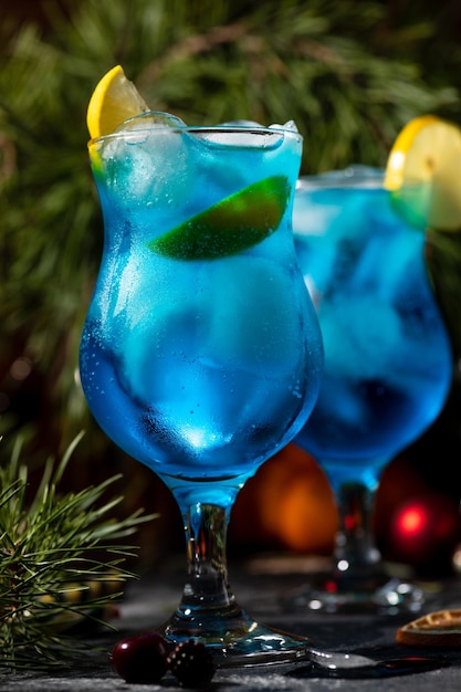 Blauwe cocktail in een groot glas met ijs en schijfjes citroen op een houten ondergrond