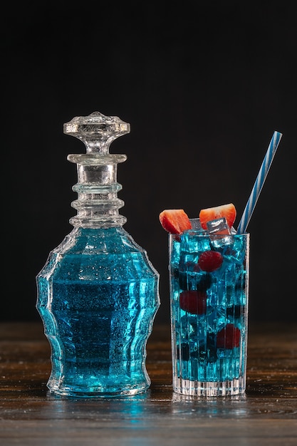 Blauwe cocktail in vintage karaf en in een glas op houten tafel