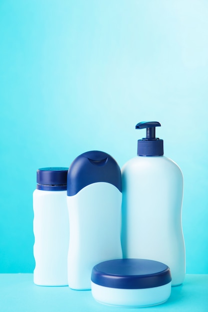 Blauwe cosmetische flessen op blauwe muur met kopie ruimte. Bovenaanzicht
