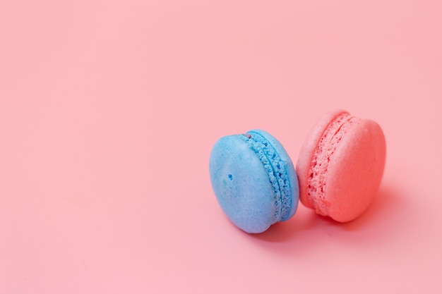 Blauwe en roze bitterkoekjes op roze achtergrond.