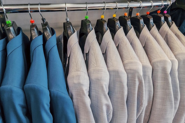 Blauwe en witte pakken hangen aan de houten kleerhanger van een kledingwinkel voor mannen met een gezellige en zakenmanstijl. officiële mannen dragen in de winkel