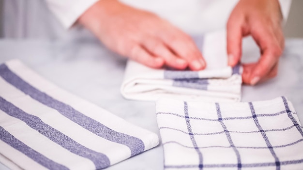 Blauwe en witte papieren handdoeken met patroon op een marmeren oppervlak vouwen.