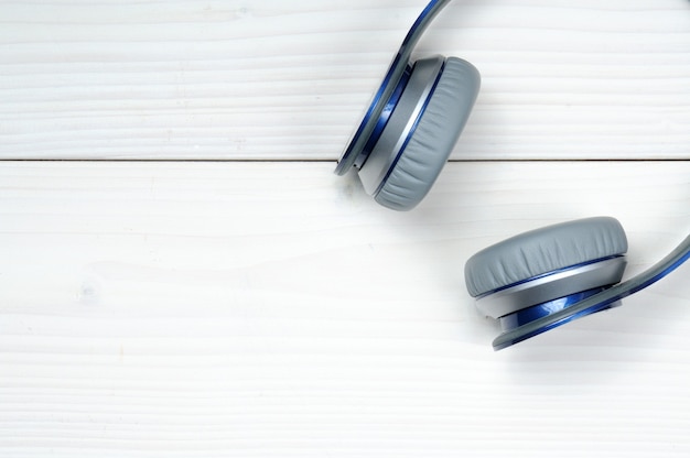 Blauwe en zilveren moderne koptelefoon voor het luisteren naar muziek op een wit hout