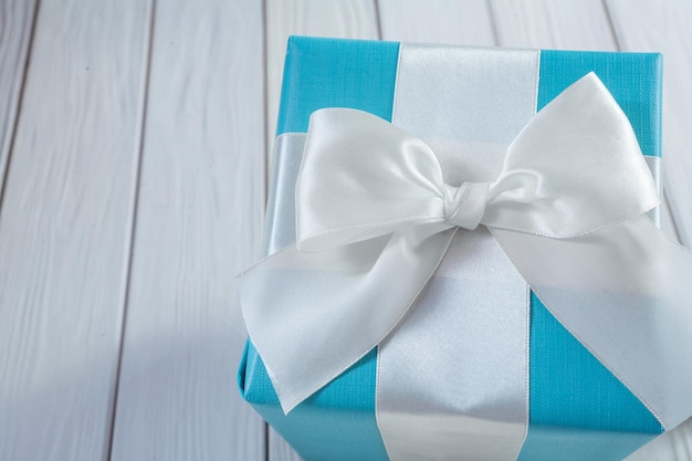 Blauwe geschenkdoos met witte strik op witte houten tafel