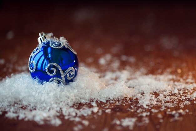 Blauwe glazen bol. Kerst speelgoed. In een stapel sneeuw, hout getextureerde tafel, rustieke stijl