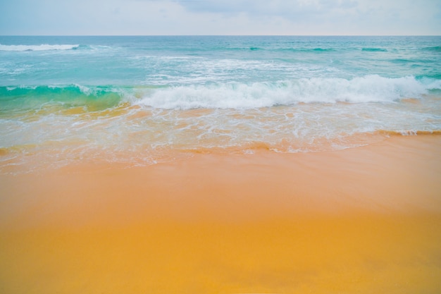 Blauwe golven van de oceaan en het gele zand van het strand.