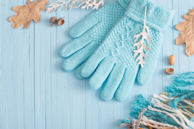 Blauwe handschoenen en herfstbladeren op houten achtergrond