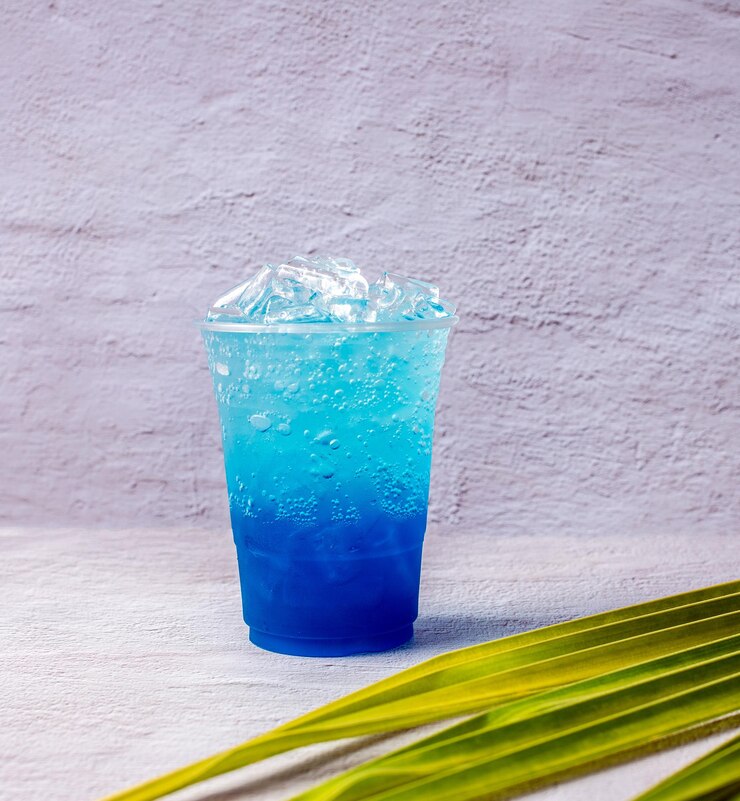 Blauwe Hawaïaanse drank in een plastic glas en kokosbladeren
