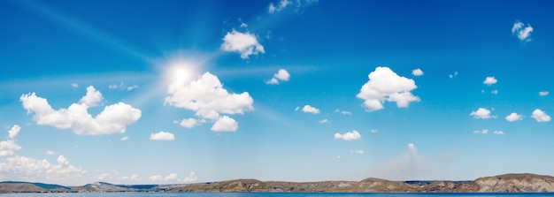 Blauwe hemel boven het zeeoppervlak met zon en wat wolken. Drie schoten steek afbeelding.