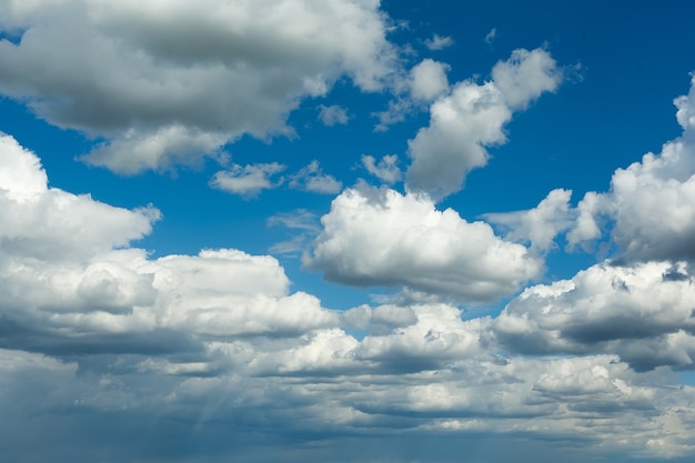 Blauwe hemelachtergrond met grote witte wolken