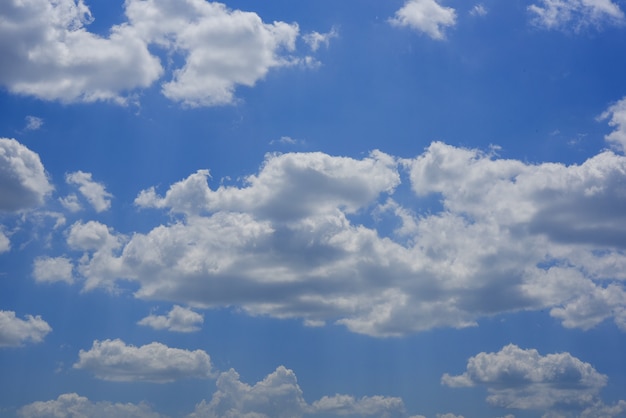 Blauwe hemelachtergrond met kleine wolken.