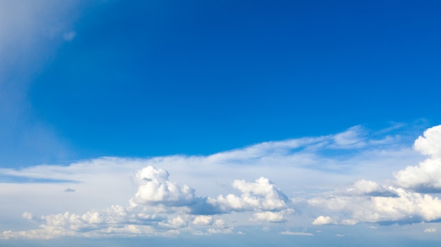 Blauwe hemelachtergrond met kleine wolken