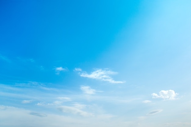 Blauwe hemelachtergrond met kleine wolken.