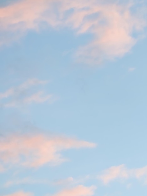 Blauwe hemelachtergrond met lichtroze wolken bij zonsondergang