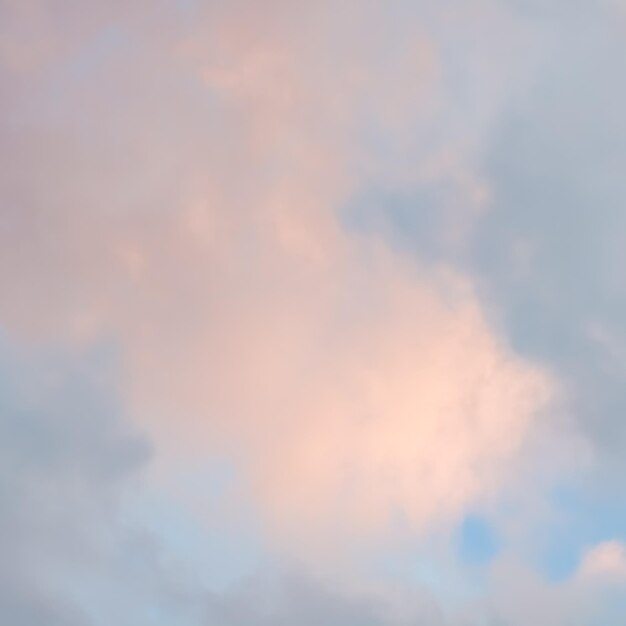 Blauwe hemelachtergrond met lichtroze wolken bij zonsondergang