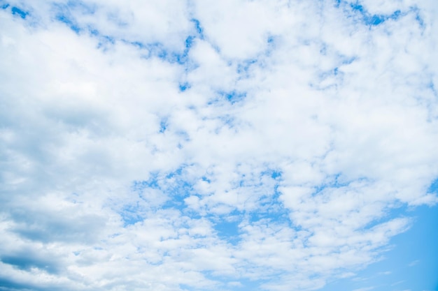 Blauwe hemelachtergrond met witte pluizige wolken