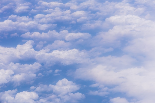 Blauwe hemelachtergrond met witte wolken op zonnige dag.