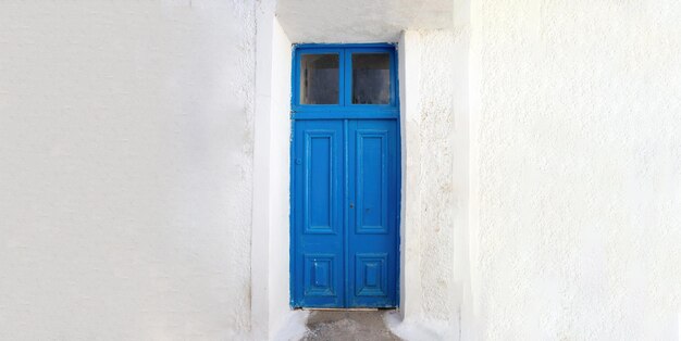 Blauwe houten deur op een lege witte muur achtergrond Grieks eiland huis voorkant