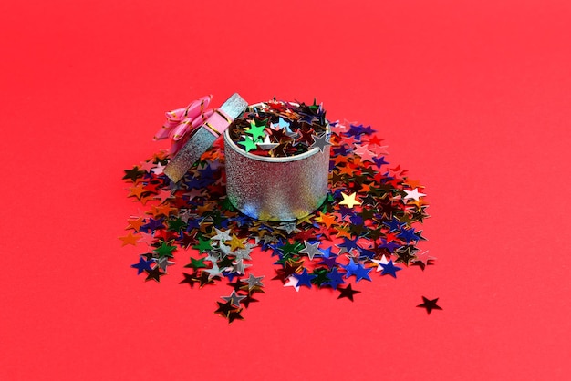 Blauwe huidige doos met roze strik en confetti op een rode achtergrond