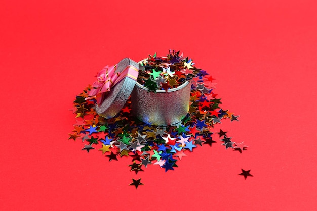 Blauwe huidige doos met roze strik en confetti op een rode achtergrond