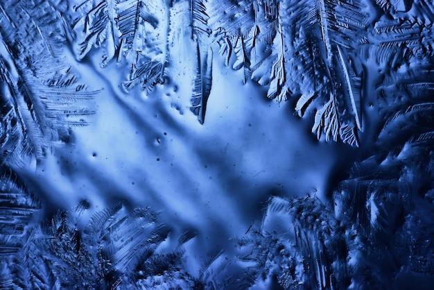 blauwe ijsglasachtergrond, abstracte textuur van het oppervlak van het ijs op het glas, bevroren seizoenswater