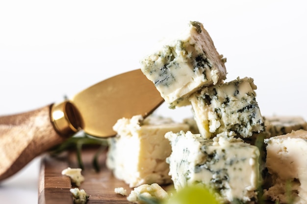 Foto blauwe kaas met een kaasmes op een houten bord tegen de achtergrond van druiven