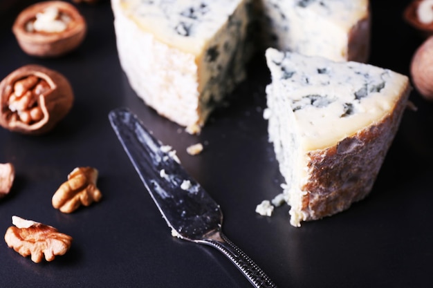 Foto blauwe kaas met noten en mes op metalen achtergrond