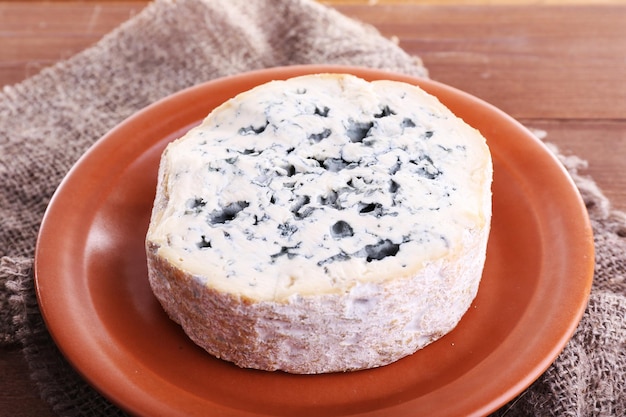 Foto blauwe kaas op aardewerk schotel op jute doek en houten tafel achtergrond