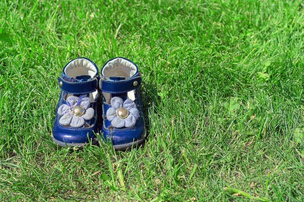 Blauwe kindersandalen op groen gras. Leuke meisjesschoenen in de tuin. Het concept van kindertijd en zomer
