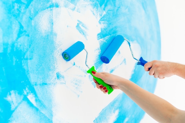 Blauwe kleur schilderij muur met roller in de hand.