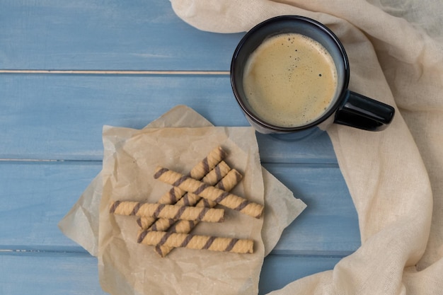 Blauwe kop koffie en wafelbroodjes op een houten tafel