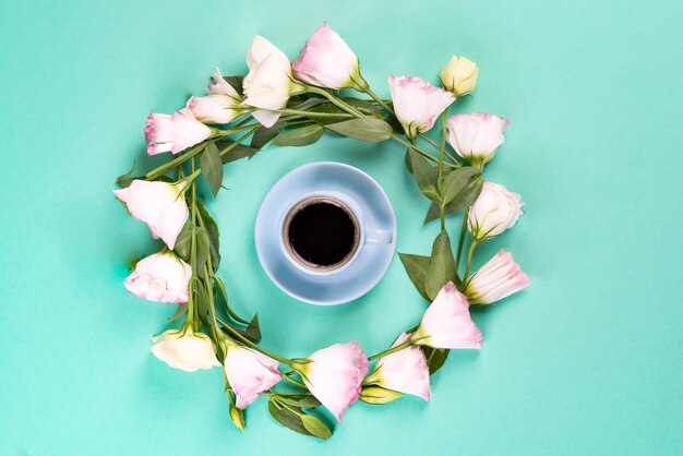 Blauwe kop koffie met krans gemaakt van roze bloemen eustoma