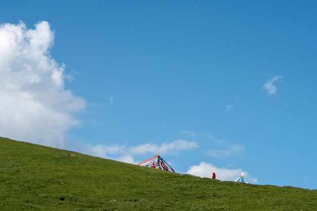 blauwe lucht en witte wolken naast het Qinghai-meer, evenals enkele tenten en gebedsvlaggen op grasland