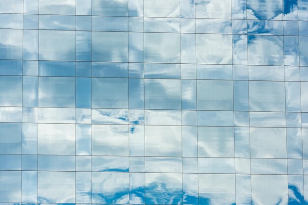 Blauwe lucht en wolken weerspiegeld in ramen van modern kantoorgebouw