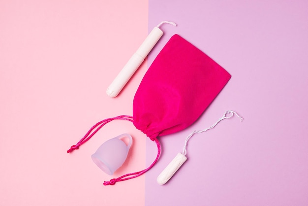 Blauwe menstruatiecup roze zak Tampons op roze en lila achtergrond Vrouw gezondheid en milieuvriendelijk vrouwelijke hygiëne Productconcept bovenaanzicht