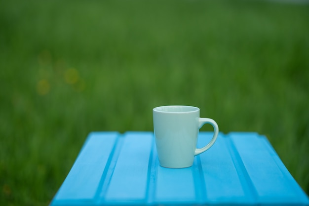 Blauwe mok op een houten tafel en groen gras