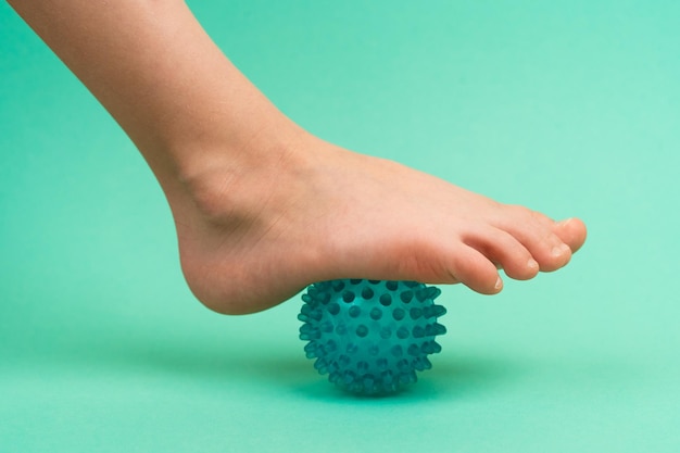 Blauwe naaldbal voor massage en fysiotherapie op een groene achtergrond met een child39s-voet het concept preventie en behandeling van voetvalgus