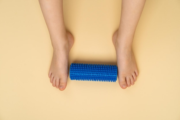 Foto blauwe naaldrol voor massage en fysiotherapie op een beige achtergrond met de afbeelding van een kindervoet het concept van preventie en behandeling van hallux valgus