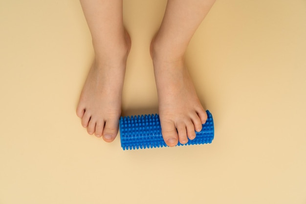 Blauwe naaldrol voor massage en fysiotherapie op een beige achtergrond met de afbeelding van een kindervoet het concept van preventie en behandeling van hallux valgus