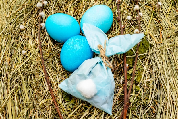 Blauwe paaseieren en konijntjes papieren zak in een nest