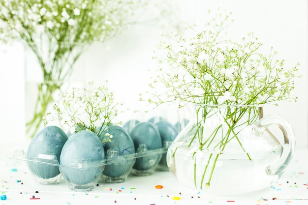 Blauwe paaseieren op een witte lijst onder boeketten van gypsophila