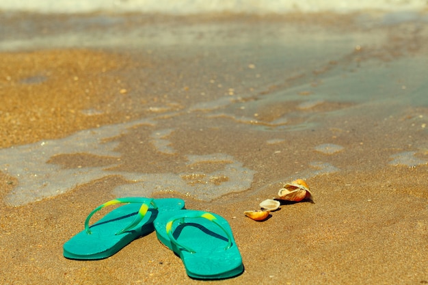 Foto blauwe pantoffels staan op het zand aan de kust