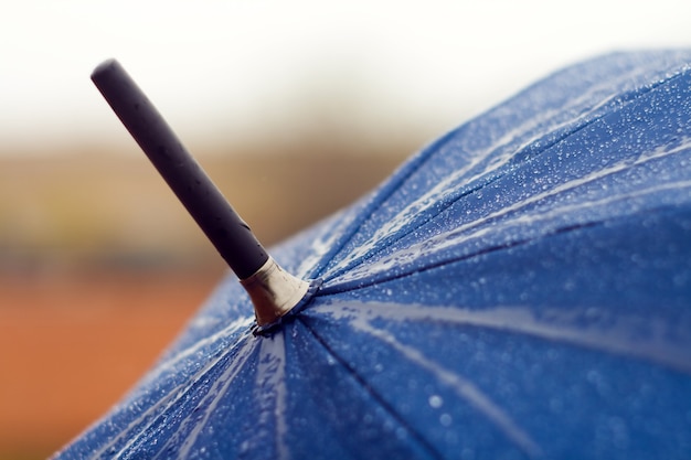 Blauwe paraplu close-up met regendruppels erop