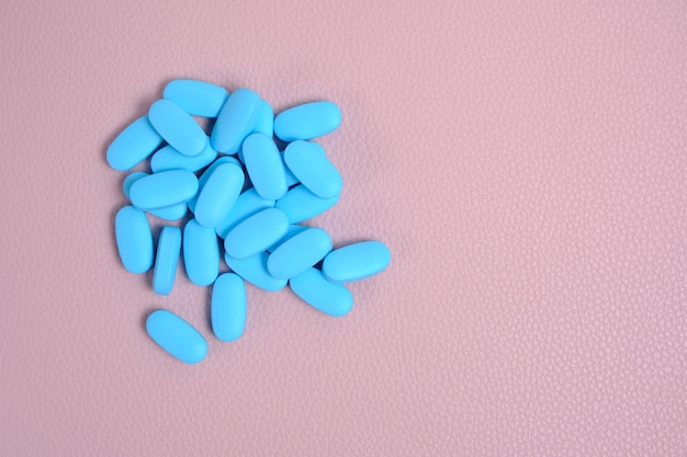 Blauwe pillen, vitamines op een roze achtergrond.