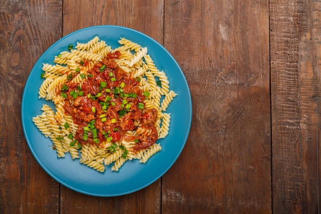 Blauwe plaat met bolognese pasta op een houten tafel kopie ruimte