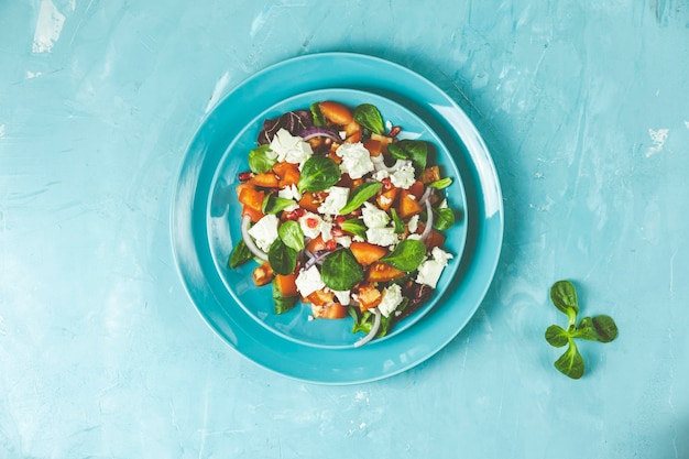 Blauwe plaat van verse superfoods gezonde salade met rode ui, tomaten, doucette, lamssla, veldsla, veldsla en fetakaas. Lichtblauw oppervlak bovenaanzicht plat lag kopie ruimte