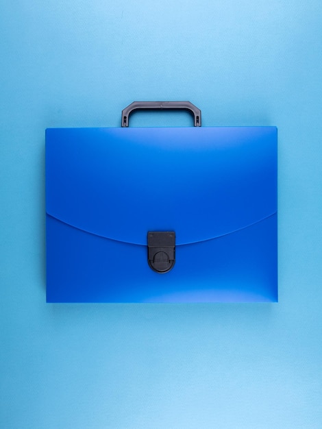 Blauwe plastic koffermap voor documenten en schoolspullen op een helderblauwe tafel