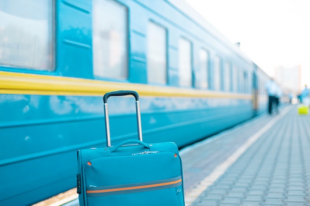 Blauwe reisbagage op het treinstation in de buurt van de spoorweg op het stadsstraatavontuur