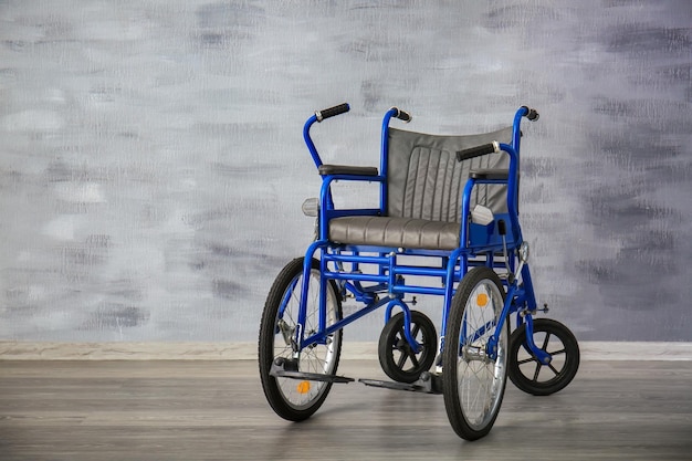 Blauwe rolstoel in de buurt van grijze muur binnenshuis