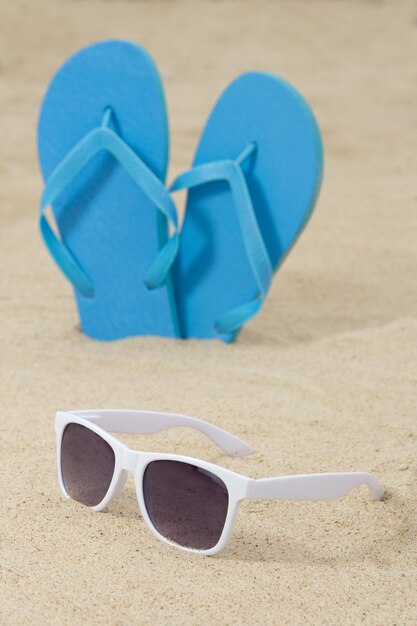 Foto blauwe rubberen slippers en zonnebrillen op het zand